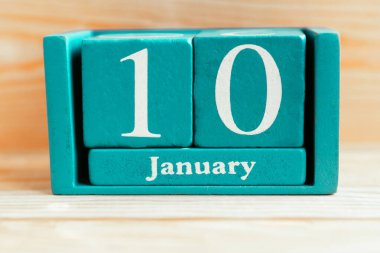 10 Ocak. Ahşap zemin üzerinde ay ve tarih olan mavi küp takvimi.