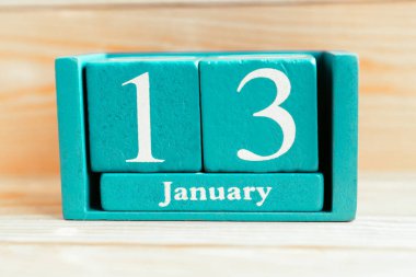 13 Ocak. Ahşap zemin üzerinde ay ve tarih olan mavi küp takvimi.