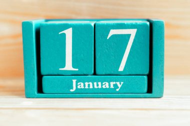 17 Ocak. Ahşap zemin üzerinde ay ve tarih olan mavi küp takvimi.