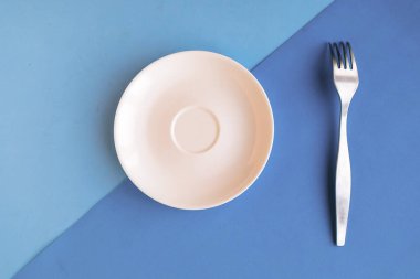 Gri ve mavi arka planda boş tabak ve çatal. Metin için alanı kopyala. Asgari konsept