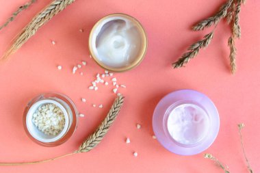 Pembe pastel arka planda doğal kozmetik ürünleri.