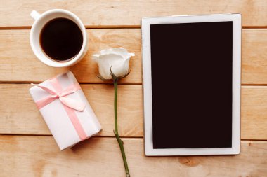 Gül, hediye kutusu ve tahta arka planda maket tableti, üst görünüm