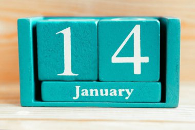 14 Ocak. Ahşap zemin üzerinde ay ve tarih olan mavi küp takvimi.