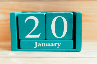 20 Ocak. Ahşap zemin üzerinde ay ve tarih olan mavi küp takvimi.