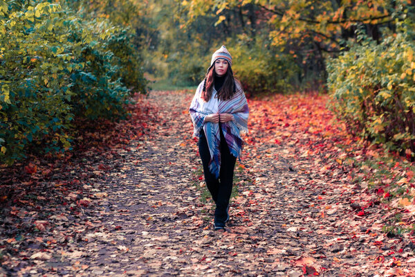 Beautiful young woman walking through an autumn park, fall background