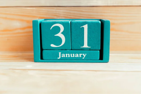 January 31. Blue cube calendar with month and date on wooden background.