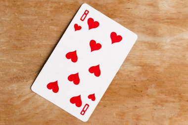 Kupa Sekizlisi iskambil oynuyor, tahta arka plan.