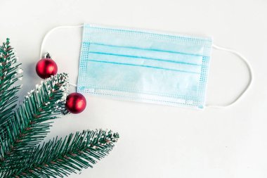 Beyaz arka planda noel ağacı dalları ve yüz maskesi, koronavirüs Noel konsepti