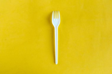 Sarı zemin üzerinde plastik çatal, üst görünüm