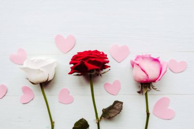 Ahşap arka planda üç gül, üst manzara. Sevgililer Günü tebrik kartı.