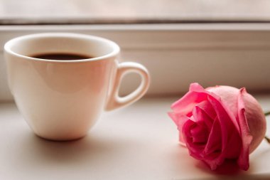 Kahve fincanı ve pembe gül pencere eşiğinde, yakın plan.
