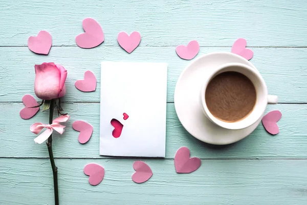 Coffee cup, card and rose on wooden table, top view. Valentine Day greeting card
