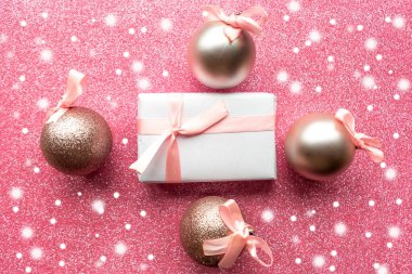 Hediye kutusu ve pembe parıltılı arka planda takılar, üst manzara. Mutlu Noeller ve mutlu yıllar. Noel tebrik kartı.