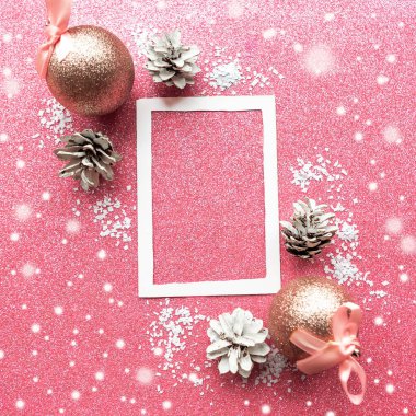 Pembe parıltılı arka planda fotoğraf çerçevesi ve takılar. Noel tebrik kartı şablonu
