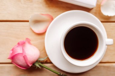 Kahve fincanı ve gül ahşap arka planda, üst manzara