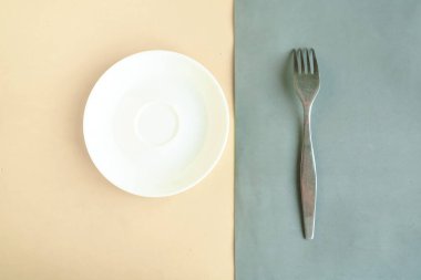 Gri ve sarı arka planda boş tabak ve çatal. Metin için alanı kopyala. Asgari konsept