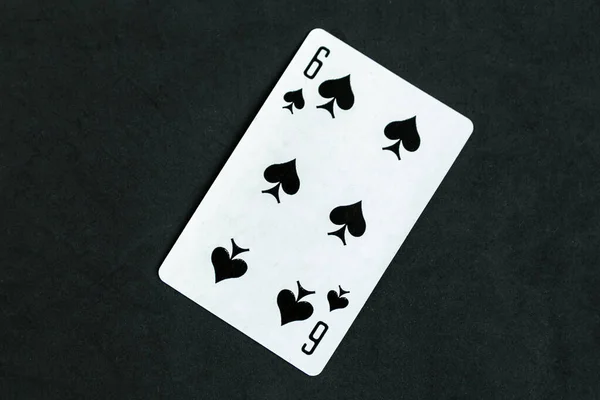 Six of Spades playing card, black background, top view