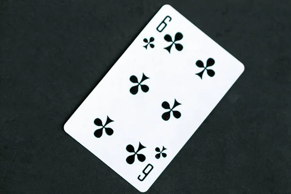 Six of Clubs playing card, black background, top view