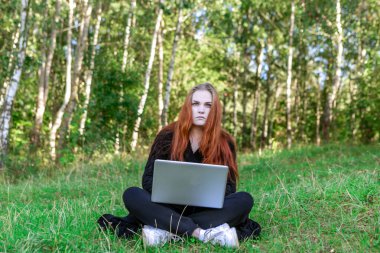Doğada serbest çalışan biri. Kadın ormanda dizüstü bilgisayarla çalışıyor..