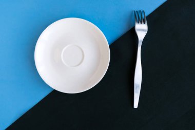 Renk geometrik arkaplanı üzerinde boş tabak ve çatal, minimal konsept, metin için kopyalama alanı