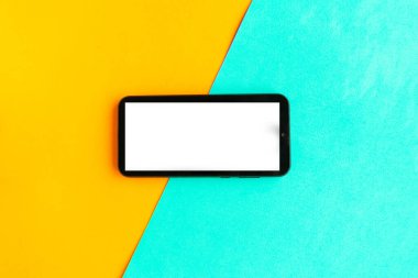 Renkli geometrik arkaplan üzerinde beyaz model ekranlı cep telefonu. 