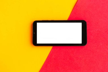 Renkli geometrik arkaplan üzerinde beyaz model ekranlı cep telefonu. 