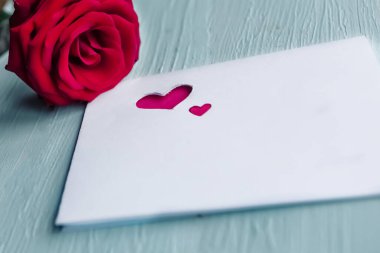 Masada kırmızı gül ve beyaz maket kartı var. Sevgililer Günü tebrik kartı.