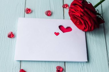 Masada kırmızı gül ve beyaz maket kartı var. Sevgililer Günü tebrik kartı.