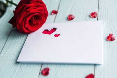 Masada kırmızı gül ve beyaz maket kartı var. Sevgililer Günü tebrik kartı.