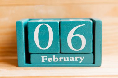 6 Şubat. Ahşap zemin üzerinde ay ve tarih olan mavi küp takvimi.