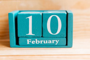 10 Şubat. Ahşap zemin üzerinde ay ve tarih olan mavi küp takvimi.