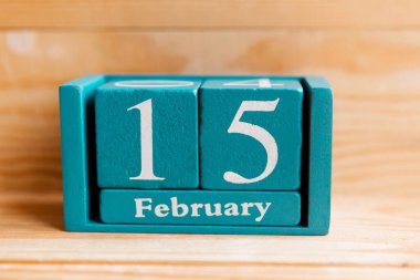15 Şubat. Ahşap zemin üzerinde ay ve tarih olan mavi küp takvimi.