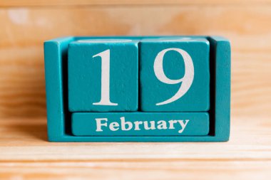19 Şubat. Ahşap zemin üzerinde ay ve tarih olan mavi küp takvimi.