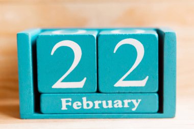22 Şubat. Ahşap zemin üzerinde ay ve tarih olan mavi küp takvimi.