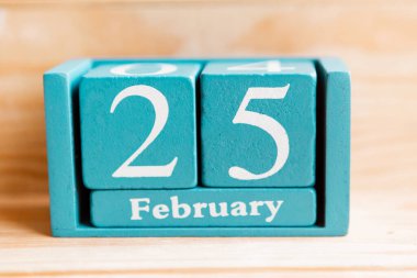 25 Şubat. Ahşap zemin üzerinde ay ve tarih olan mavi küp takvimi.
