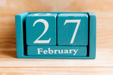 27 Şubat. Ahşap zemin üzerinde ay ve tarih olan mavi küp takvimi.