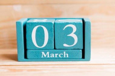 3 Mart. Ahşap zemin üzerinde ay ve tarih olan mavi küp takvimi.