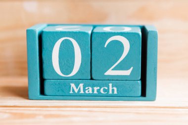 2 Mart. Ahşap zemin üzerinde ay ve tarih olan mavi küp takvimi.