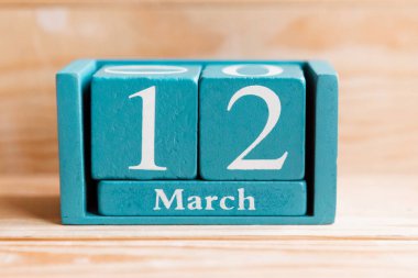 12 Mart. Ahşap zemin üzerinde ay ve tarih olan mavi küp takvimi.