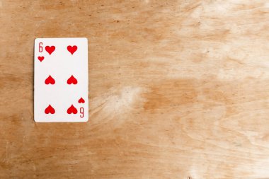 Six of Hearts playing card, wooden background, copy space