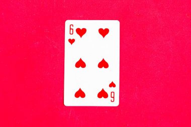 Six of Hearts playing card on red background, top view