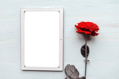 Ahşap arka planda kırmızı gül ve maket tableti. Sevgililer Günü tebrik kartı.