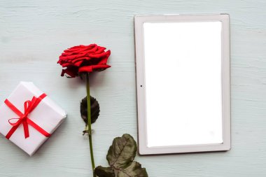 Ahşap arka planda kırmızı gül ve maket tableti. Sevgililer Günü tebrik kartı.