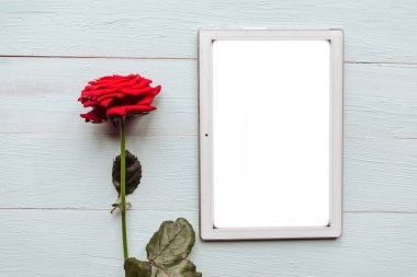 Ahşap arka planda kırmızı gül ve maket tableti. Sevgililer Günü tebrik kartı.