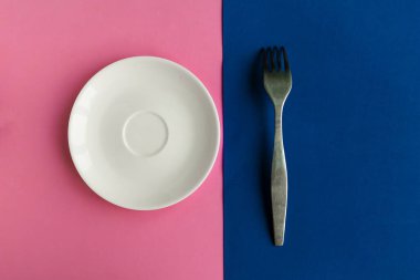 Pembe ve mavi arka planda boş tabak ve çatal. Metin için alanı kopyala. Asgari konsept