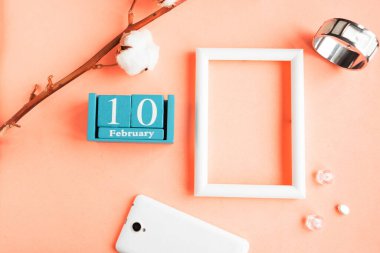 10 Şubat. Pembe pastel arka planda ay, tarih ve resim çerçeveli mavi küp takvimi.