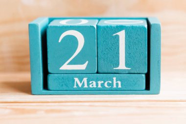 21 Mart. Ahşap zemin üzerinde ay ve tarih olan mavi küp takvimi.