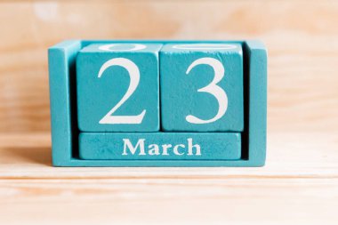 23 Mart. Ahşap zemin üzerinde ay ve tarih olan mavi küp takvimi.