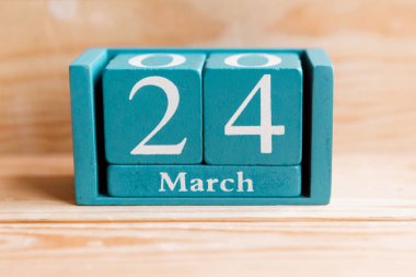 24 Mart. Ahşap zemin üzerinde ay ve tarih olan mavi küp takvimi.