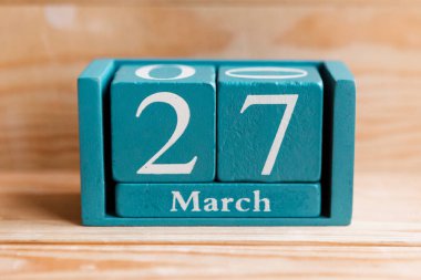 27 Mart. Ahşap zemin üzerinde ay ve tarih olan mavi küp takvimi.